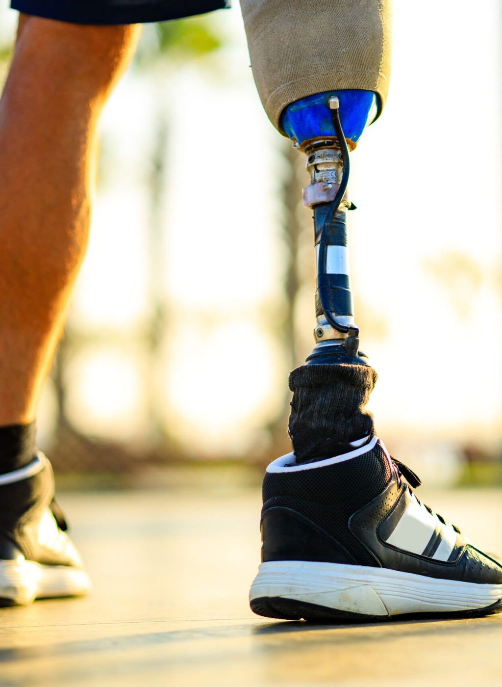 disabled athlete man with prosthetic walking at the beach outdoors at sunset.